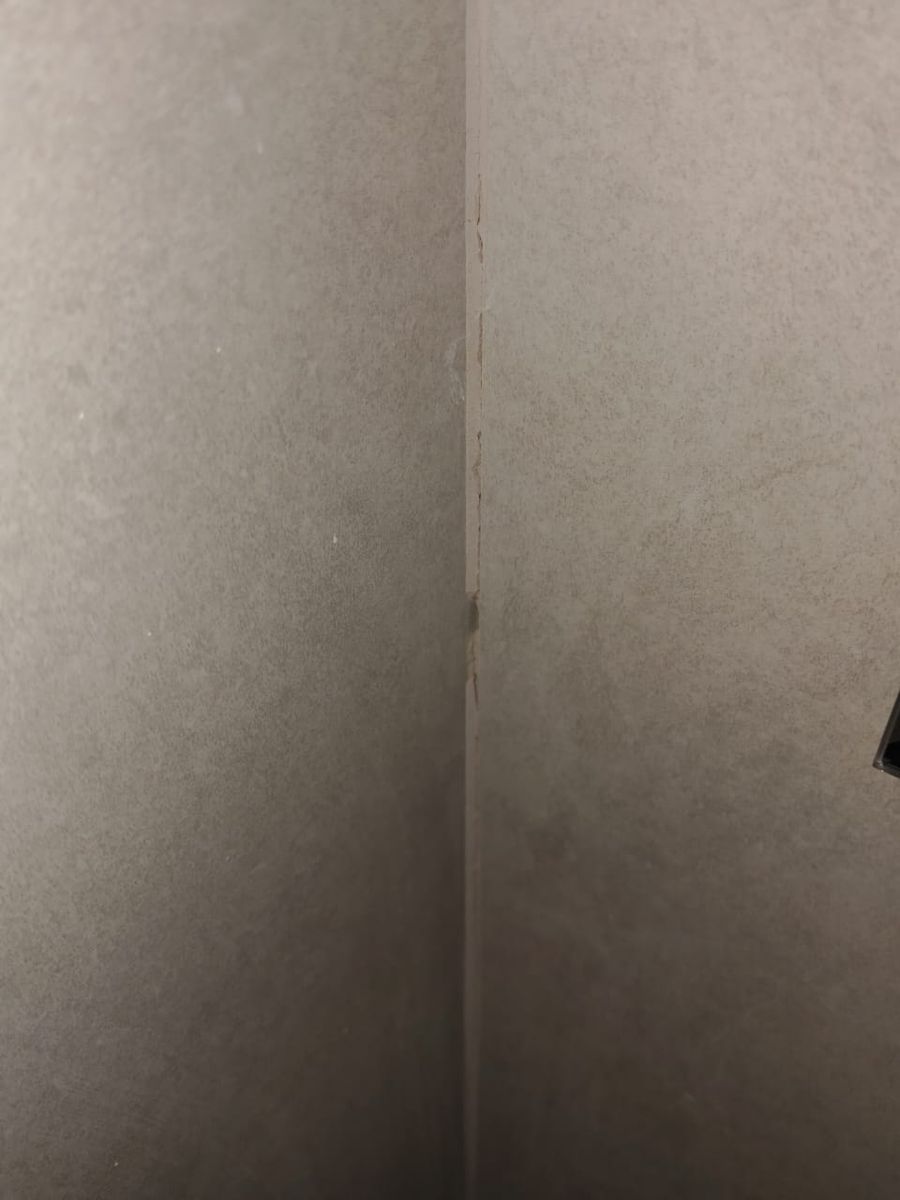 Esquina de muro de baño revestido en porcelanato con la junta vertical sin fragüe